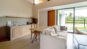 Una cocina moderna con comedor, sofá y vista a un jardín.