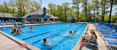 A swimming pool with lanes, lounge chairs, and a covered area with umbrellas.