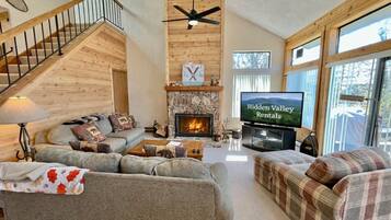 A spacious living room with a fireplace, a television, and a staircase.