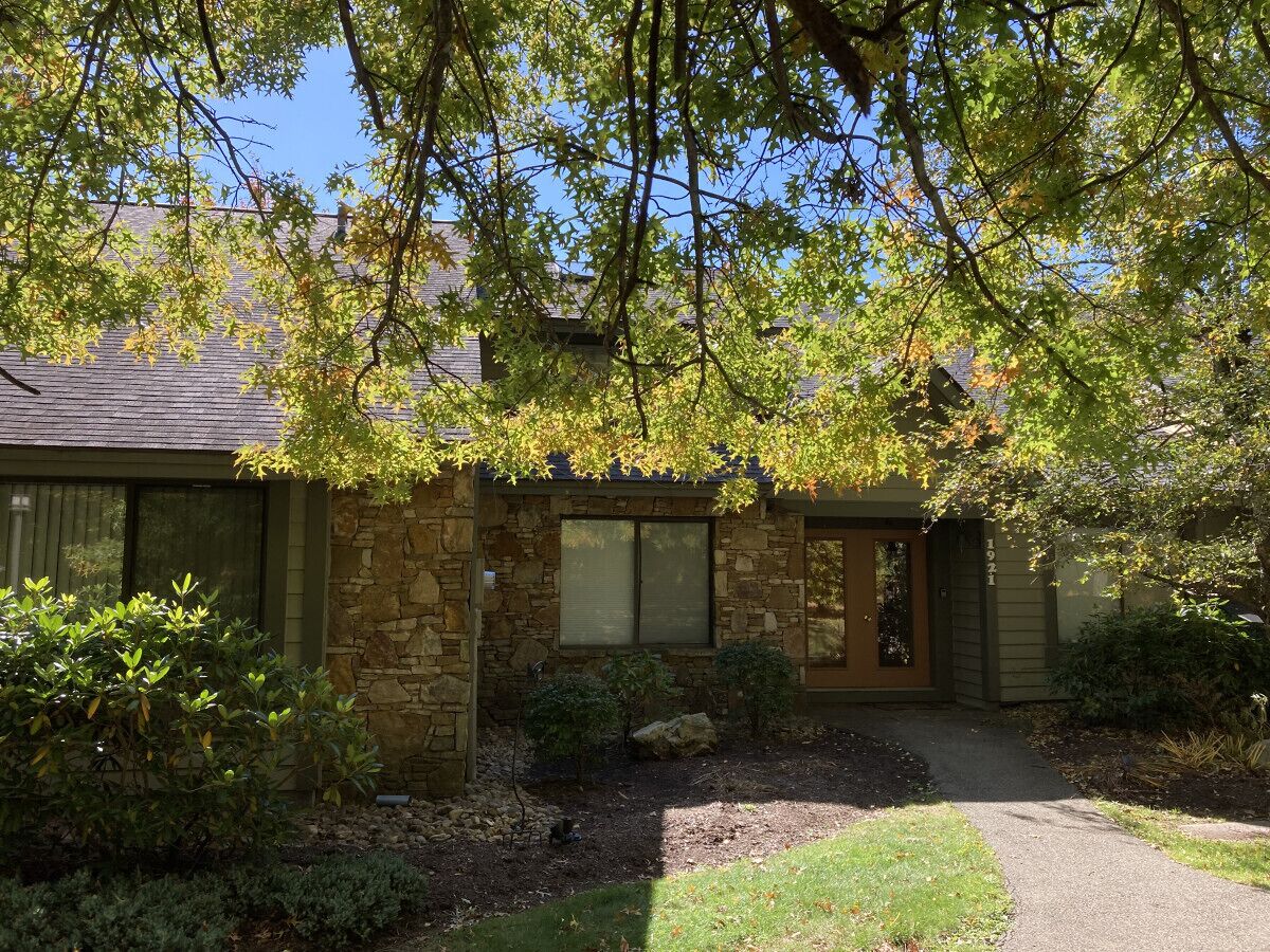 A stone house with a front porch, a small garden, and a pathway leading to the entrance.