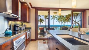 Una cocina moderna con una isla grande, armarios de madera y vista al océano.