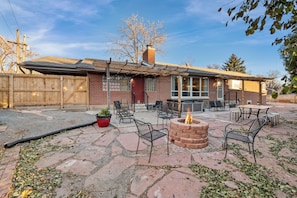 A patio area with outdoor seating, a fire pit, and a brick building with a covered patio.