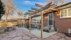 A backyard with a pergola, patio furniture, and a barbecue area.