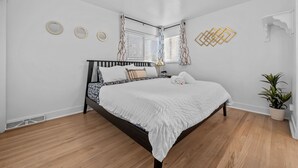 A bedroom with a bed, a potted plant, and a ceiling light.