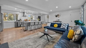 A modern kitchen with a central island, bar stools, and a dining area.