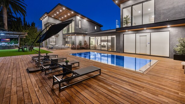 Una casa moderna con piscina, terrazza in legno e zona relax all'aperto.