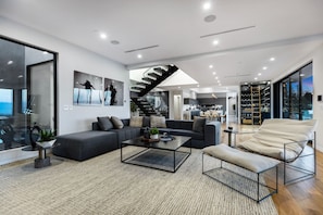 A modern living room with a sofa, coffee table, and a view of the kitchen and dining area.
