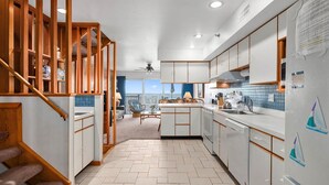 A modern kitchen with white cabinets, a wooden staircase, and a view of the sea. - Midtown 4 bedroom oceanfront townhome, steps from the beach (Ocean City)