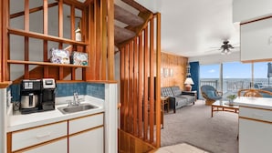A compact kitchen with a coffee maker, a sink, and wooden cabinets. There is a seating area with a sofa and chairs, and a view of the ocean through large windows. - Midtown 4 bedroom oceanfront townhome, steps from the beach (Ocean City)