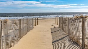 A beach pathway leading to the ocean with wooden railings and a sandy beach. - Midtown 4 bedroom oceanfront townhome, steps from the beach (Ocean City)