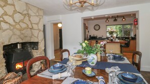 A dining area with a stone fireplace, a chandelier, and a view into the kitchen. - Brook Farm (Ringwood)