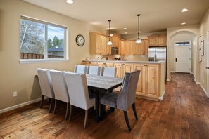 Una cocina con armarios de madera, una isla central y una zona de comedor con sillas.