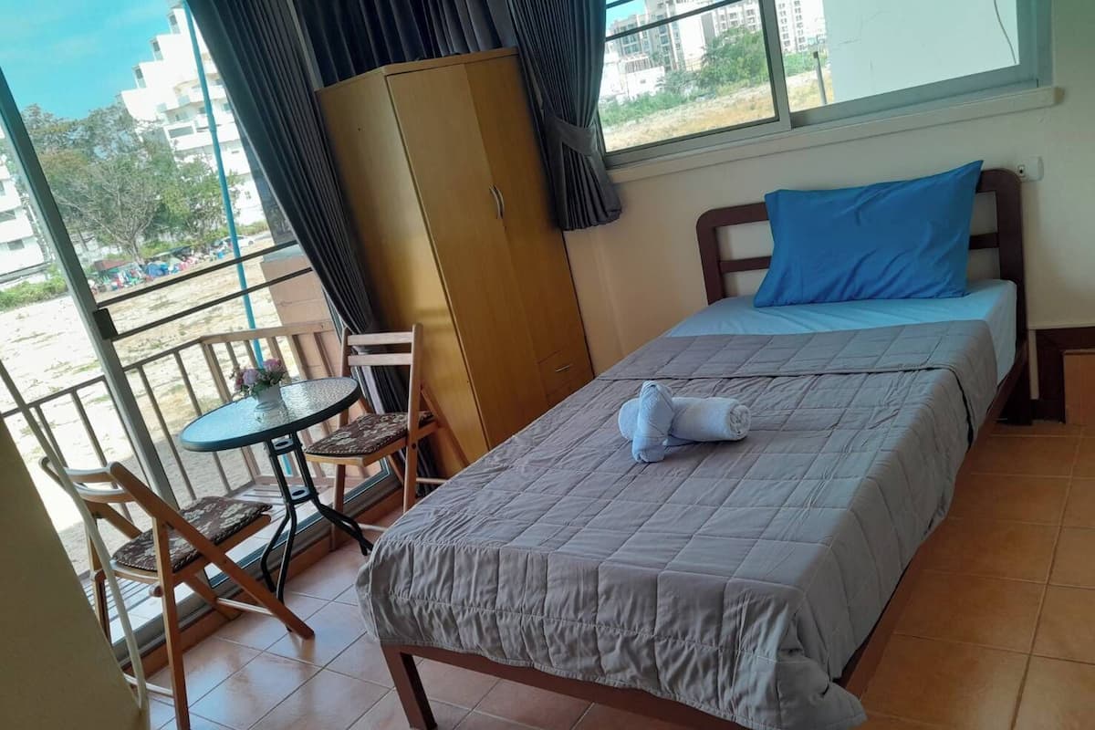 A single bedroom with a bed, a small table, and a chair.