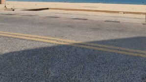 A beach with a clear sky, a sandy shore, and a road in the foreground. - White House by Sorot (Pattaya)