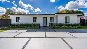 Una casa moderna de dos pisos con fachada blanca, ventanas con marcos negros y puerta negra.