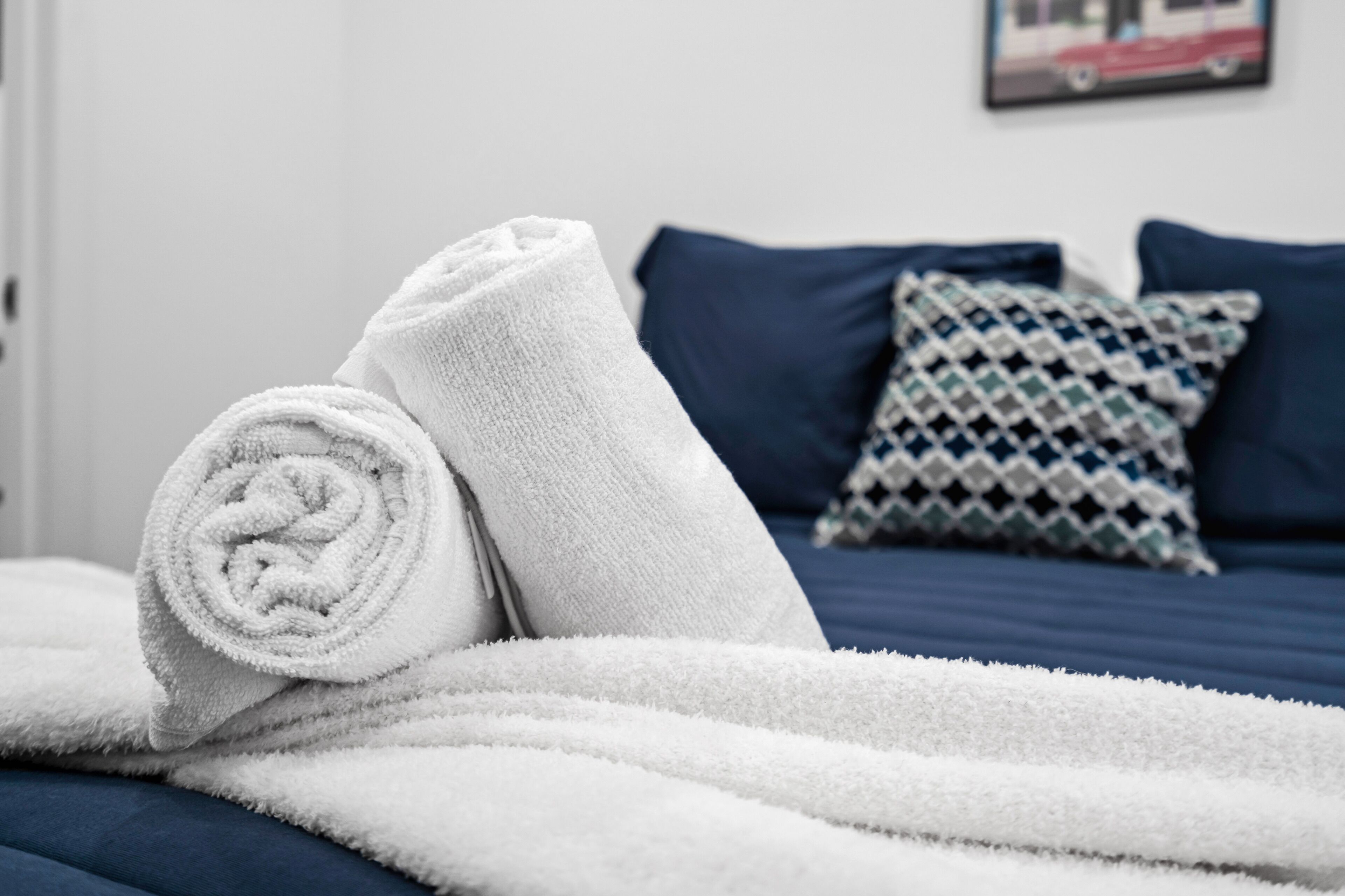 A neatly made bed with white towels and a patterned pillow.