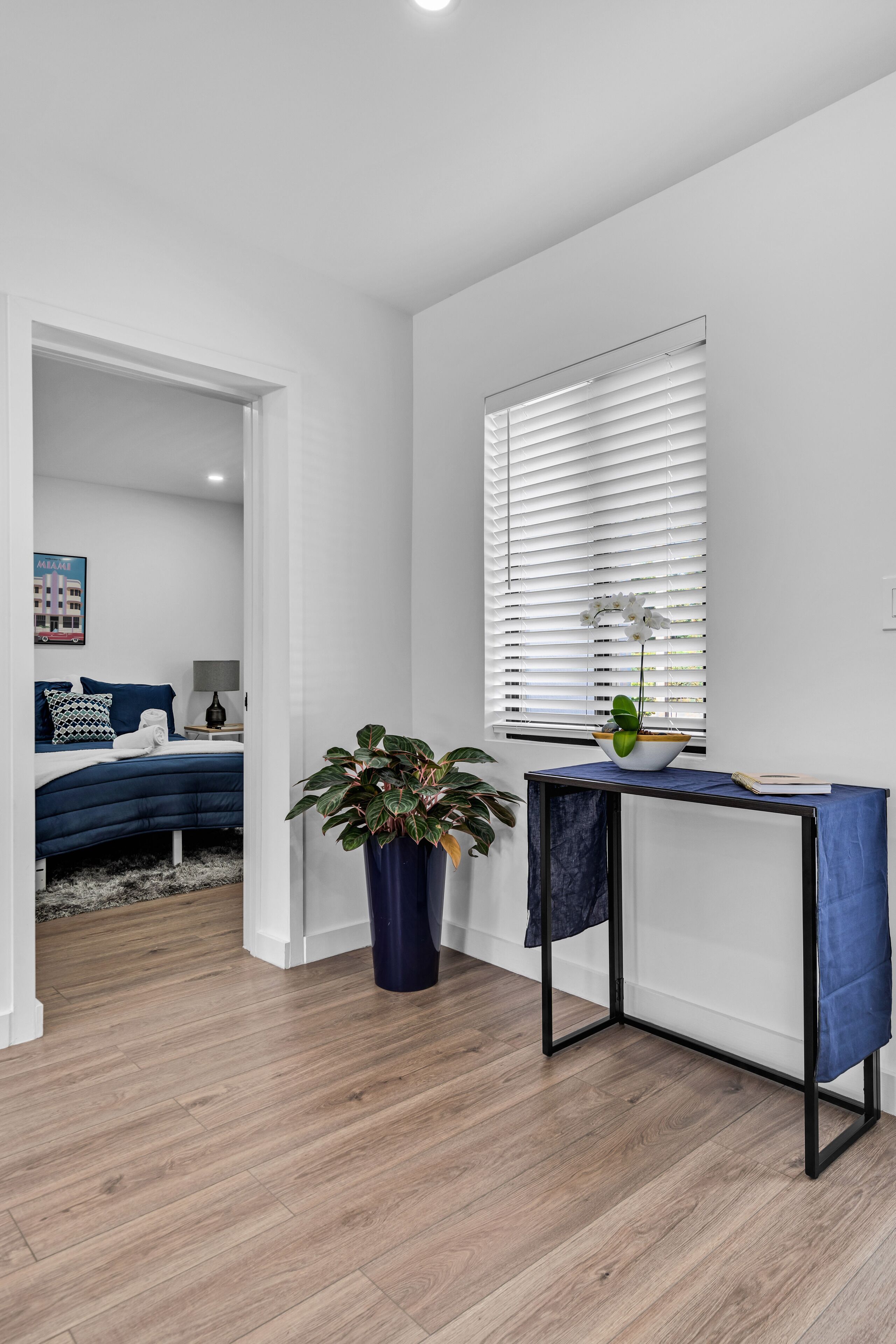 Een moderne slaapkamer met een bed, nachtkastje, lamp en een potplant.
