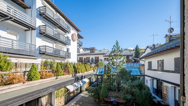 Een binnentuin met buiten zitplaatsen, een houten terras en gebouwen met balkons en ramen.