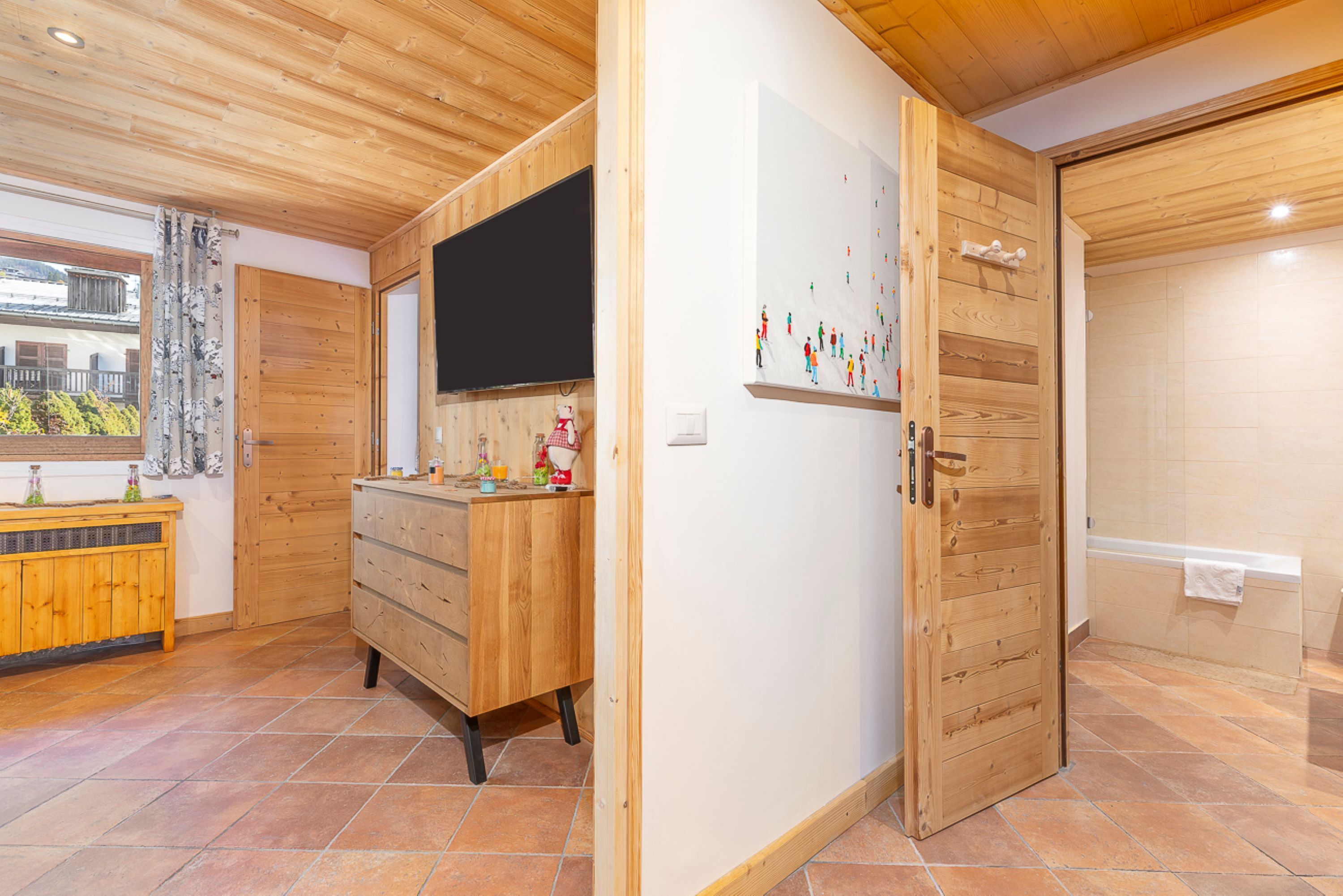 Un interior de madera con zona de cocina, televisor y baño con bañera.