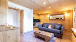 Een houten interieur met een bank, salontafel en een keukenhoek.