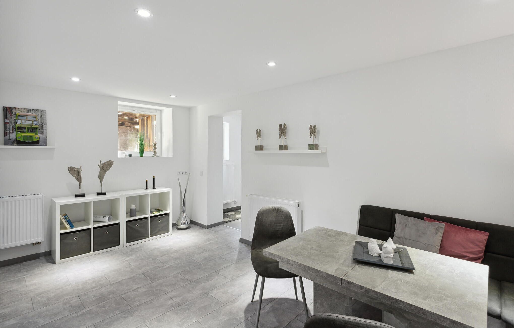 A modern kitchen with white cabinetry, a dining table with chairs, and a black sofa.