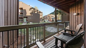 A wooden deck with a railing, a table, and two chairs. - Great Location, Minutes From Keystone Lifts w/ Patio, Shared Pool & Hot Tub! (Keystone)