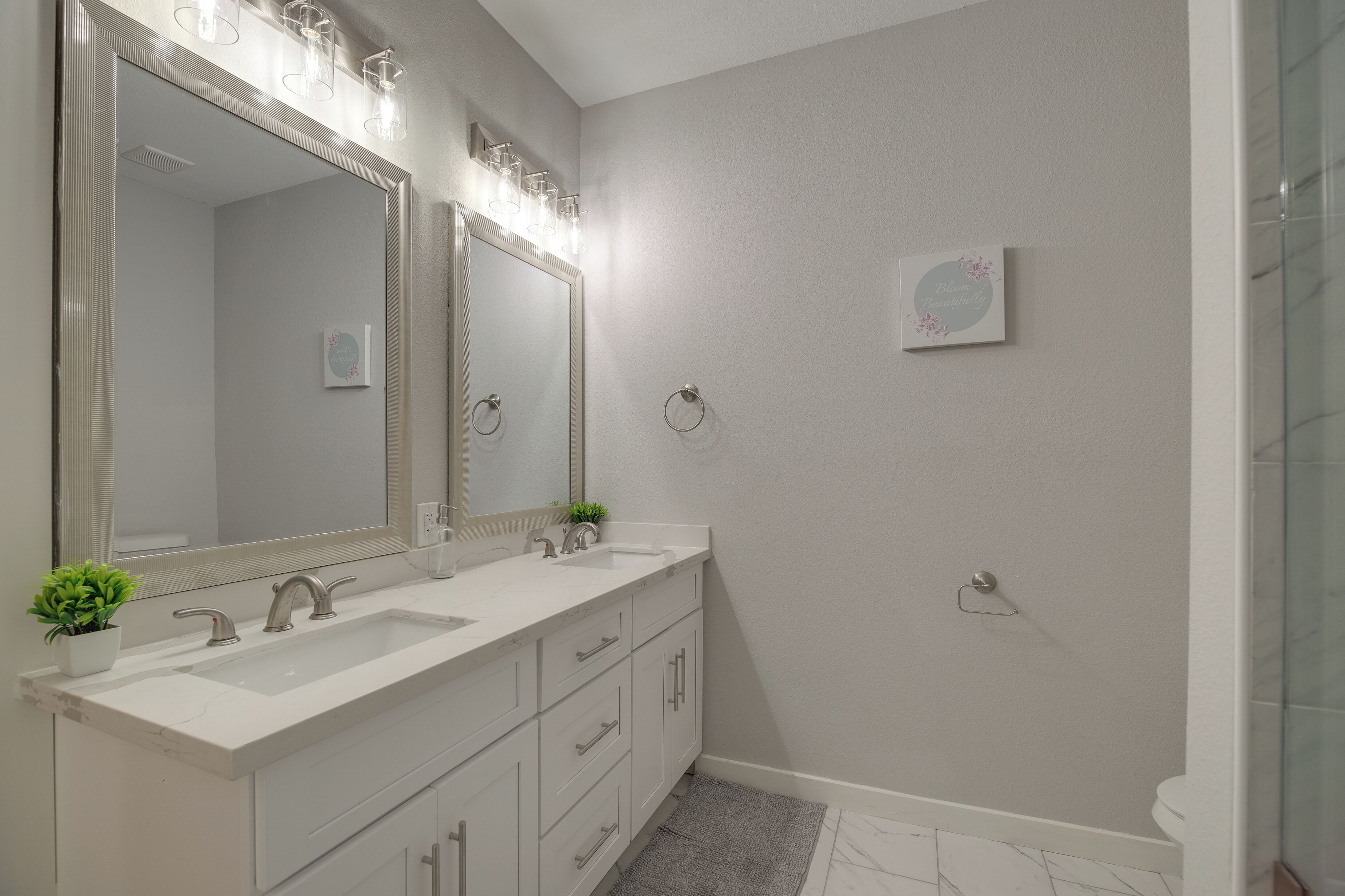 A modern bathroom with a large mirror, two sinks, and a shower.