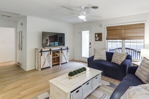 A living room with a sofa, a coffee table, a TV on a wooden stand, and a window with blinds. - 2 Mi to Bethany Beach! Family Home w/ Deck (Frankford)