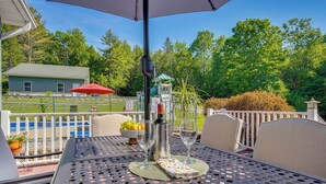 Une terrasse extérieure avec une table en métal, deux chaises, une bouteille et un verre.
