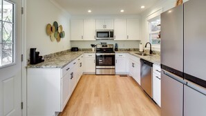 A modern kitchen with white cabinets, stainless steel appliances, and a granite countertop. - Tranquil Travelers Rest Home w/ Fire Pit! (Travelers Rest)