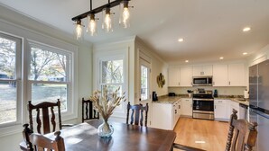 A modern kitchen with white cabinets, stainless steel appliances, and a wooden dining table with chairs. - Tranquil Travelers Rest Home w/ Fire Pit! (Travelers Rest)