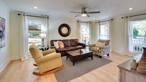 A spacious living room with a brown leather sofa, a patterned armchair, a beige rocking chair, and a dark coffee table. - Tranquil Travelers Rest Home w/ Fire Pit! (Travelers Rest)