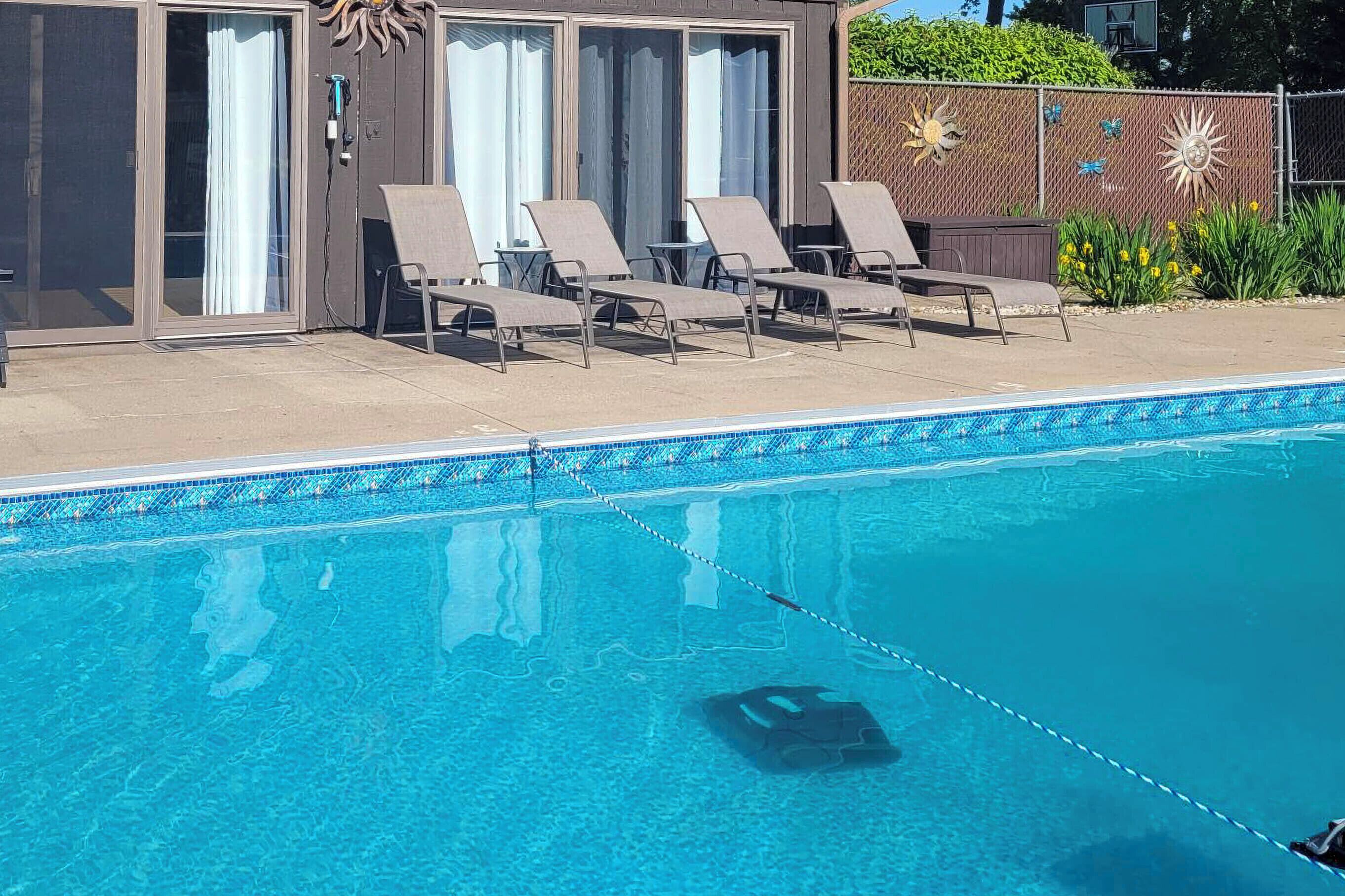A swimming pool with lounge chairs and a covered area with sliding glass doors.