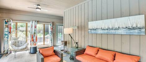 A cozy living room with wicker furniture, a large painting of sailboats, and a sign reading "Diamond Lake."