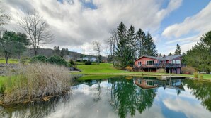 A house with a pond in front, surrounded by trees and a grassy area. - Spacious Finger Lakes Home w/ Mountain Views (Dryden)