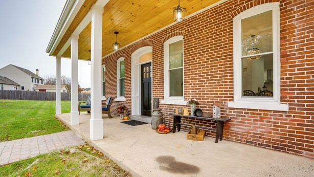 A brick house with a covered porch, a front door, and a window.