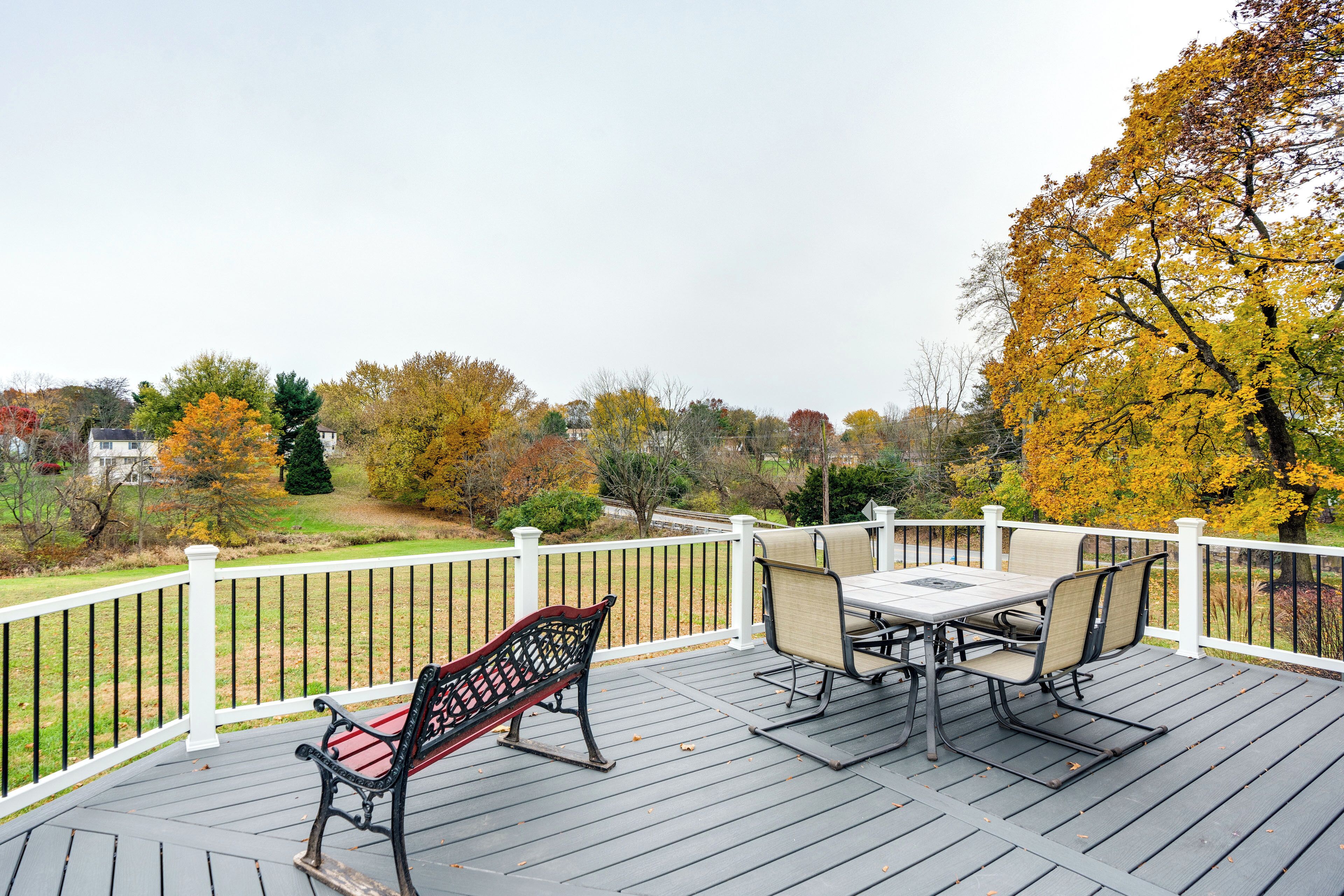 A wooden deck with a table and chairs, a bench, and a white railing.