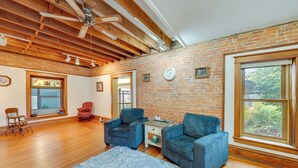 A spacious living room with wooden floors, a blue patterned rug, and two blue armchairs. - Historic Wisconsin Retreat on 26-acre Property! (Plain)