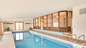 An indoor swimming pool with clear water, wooden paneling, and a view of a brick building through the windows. - Historic Wisconsin Retreat on 26-acre Property! (Plain)