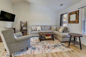 Un salon comprenant un canapé, un fauteuil, une table basse et un téléviseur fixé au mur.
