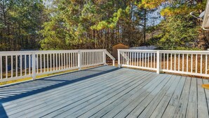 A wooden deck with white railings, surrounded by trees.