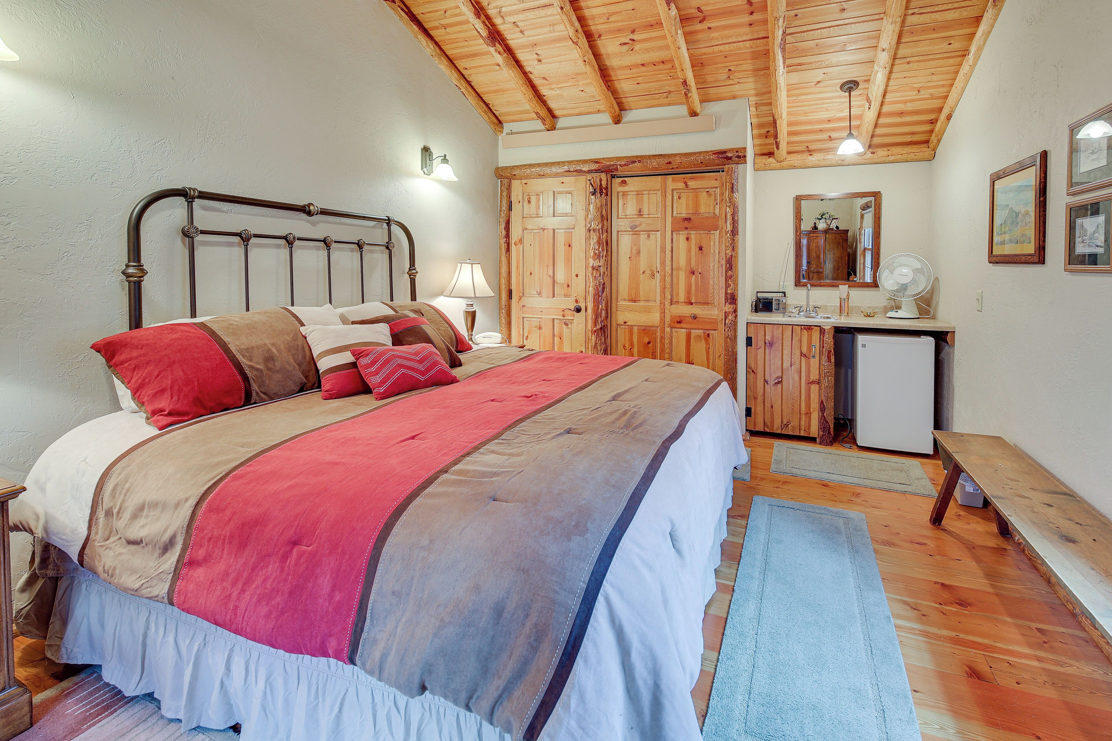 Une chambre à coucher comprenant un lit, une armoire en bois, une table de chevet, une lampe et un banc.
