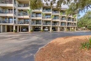 A multi-story hotel with balconies, parking, and a landscaped area.