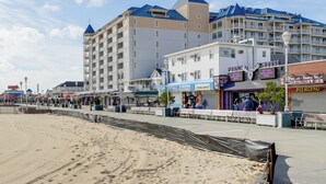 Ein Strandhotel mit mehreren Etagen, Balkonen und einem Sandstrand im Vordergrund.