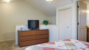 A bedroom with a bed, dresser, television, and a door. - Walk to Ocean City Beach: Condo w/ Rooftop Deck (Ocean City)