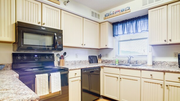 A kitchen with a stove, microwave, dishwasher, and wooden cabinets. - Walk to Ocean City Beach: Condo w/ Rooftop Deck (Ocean City)