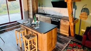 Une cuisine moderne avec un îlot central, des tabourets en bois et une grande fenêtre.