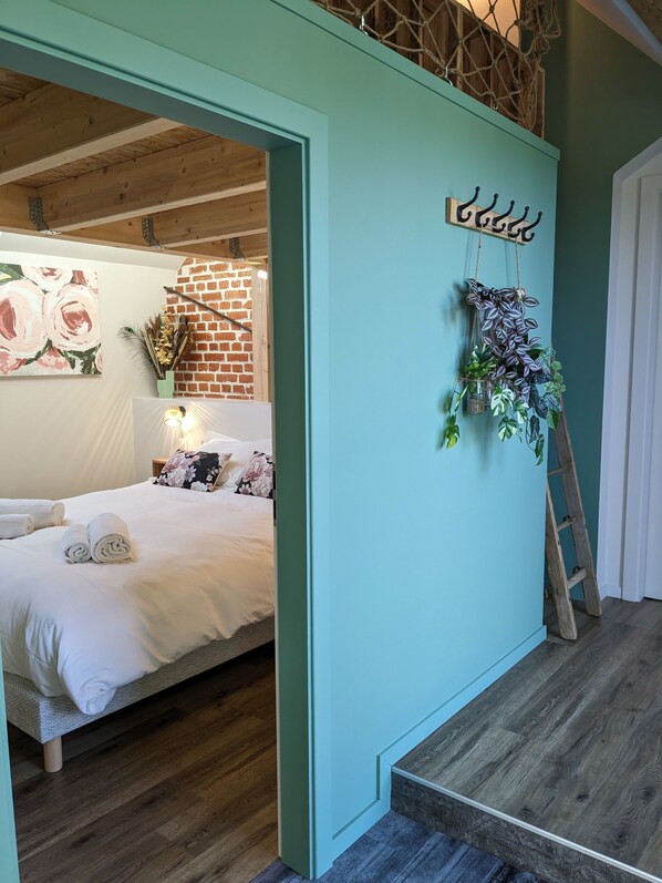 Ein Schlafzimmer mit Bett, einer hängenden Pflanze und einer Leiter.