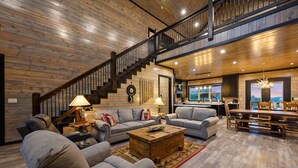A spacious living room with a wooden staircase, a dining area, and a kitchen.