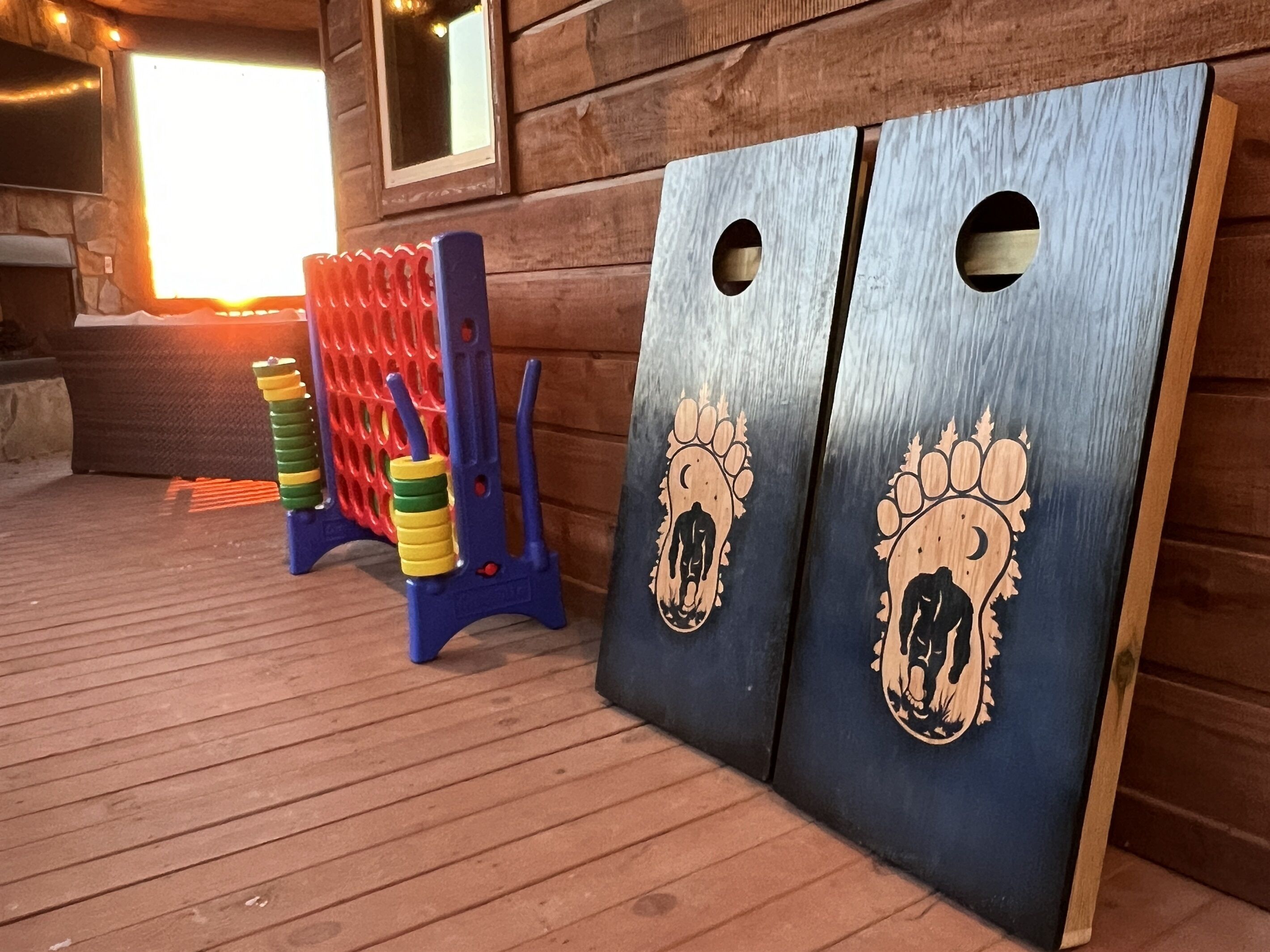 Une terrasse en bois dotée de deux grandes portes ornées d’empreintes de pattes, d’une structure d’escalade rouge et bleue, et d’une cheminée en pierre.